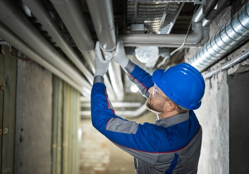 A Plumber in East Peoria IL checking the pipes in the basement of a commercial facility