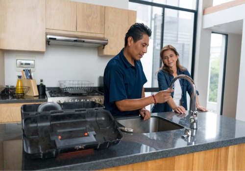 A plumber showing a woman how he repaired her sink during residential plumbing in Peoria IL